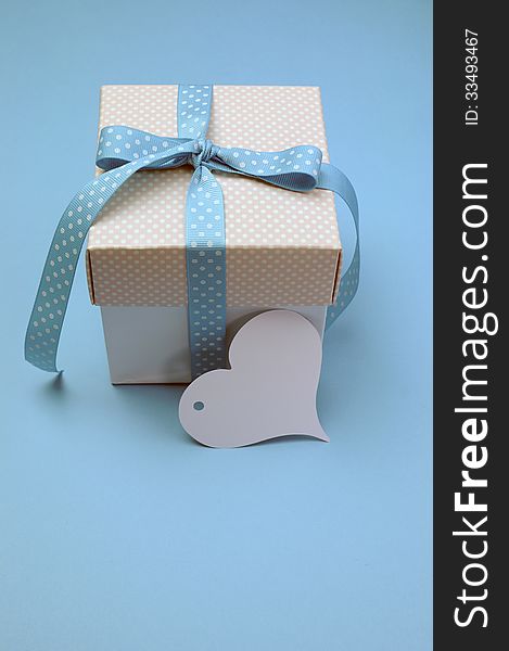 Blue and pink polka dot present with heart shape gift tag on aqua blue background for Christmas, Easter, Fathers Day or birthday present gift giving, with copy space for your text here. Blue and pink polka dot present with heart shape gift tag on aqua blue background for Christmas, Easter, Fathers Day or birthday present gift giving, with copy space for your text here.