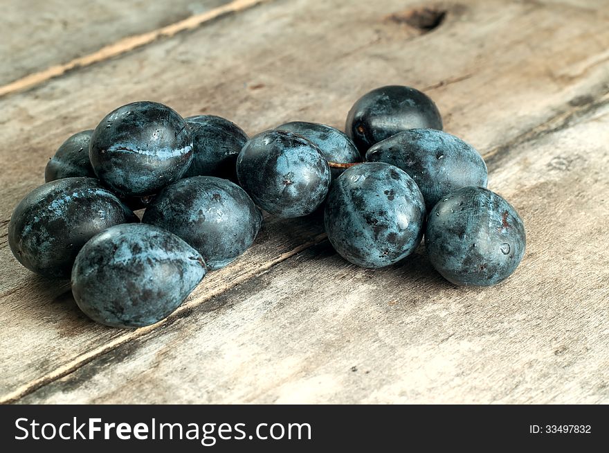 Ripe plums on old wooden table, close up