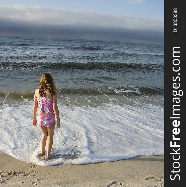 Young girl wading in surf at beach