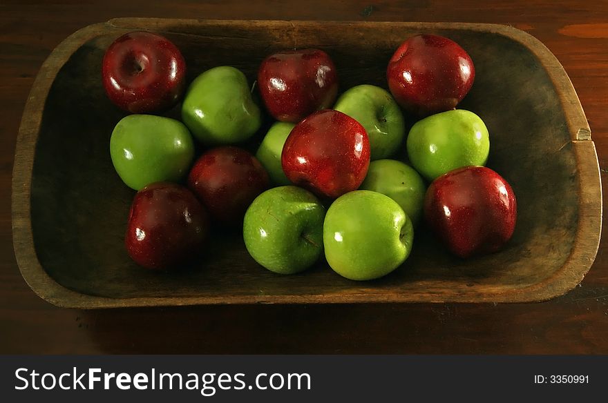 Red and green waxed apples in an antique wooden bowl. Red and green waxed apples in an antique wooden bowl.
