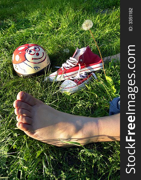 A barefoot, helmet and red snickers resting on grass after party. A barefoot, helmet and red snickers resting on grass after party