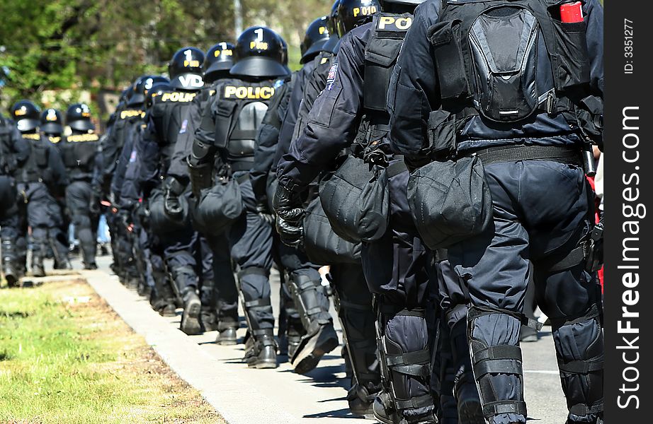 Policemen waling towards the action in a row. Policemen waling towards the action in a row