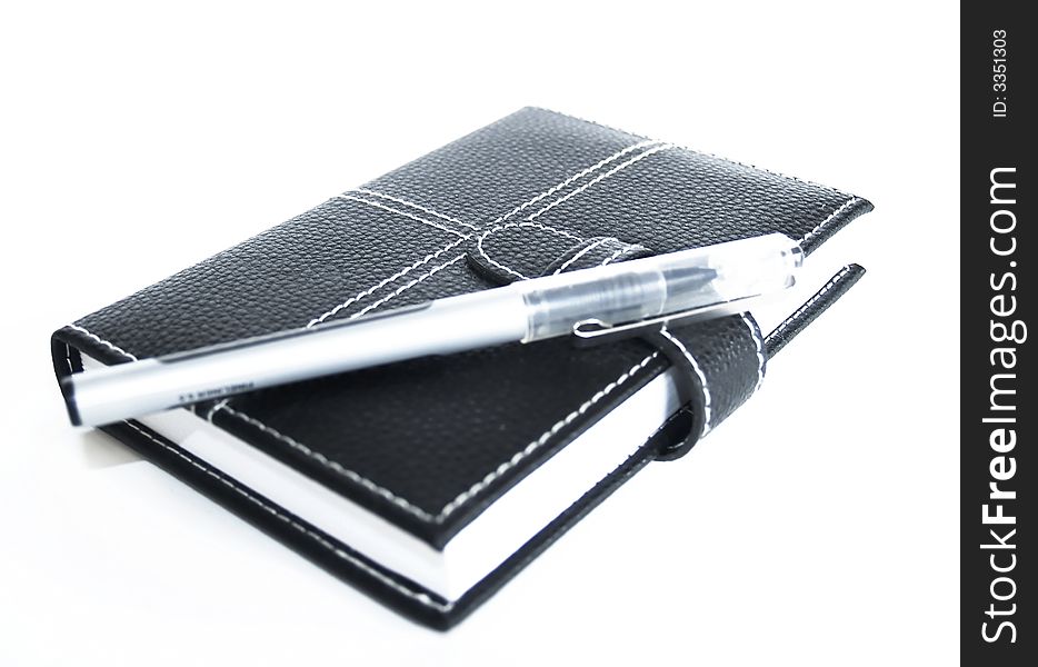 Black leather cased notebook, on white bacground with pen for writing. Black leather cased notebook, on white bacground with pen for writing.