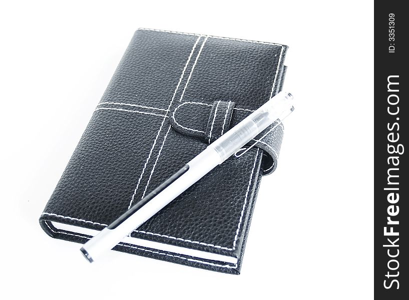 Black leather cased notebook, on white bacground with pen for writing. Black leather cased notebook, on white bacground with pen for writing.