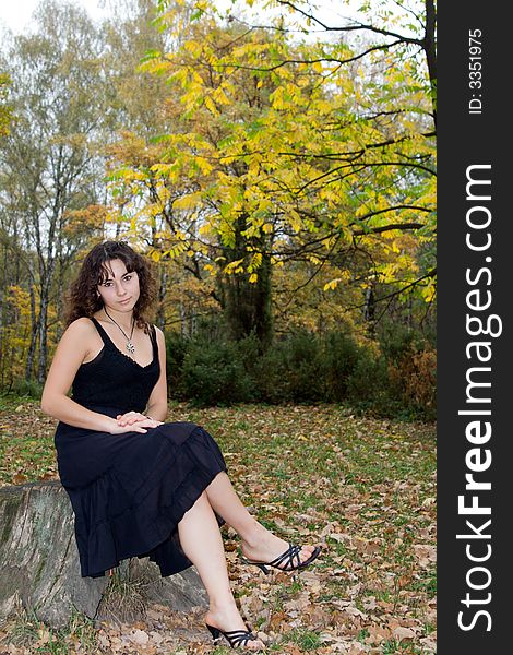 Girl with pensive look sitting at stump at autumn park. Girl with pensive look sitting at stump at autumn park.