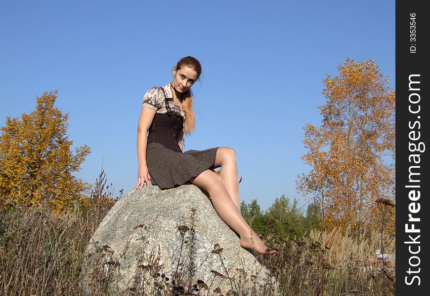 Girl On A Stone In Autumn In A Park