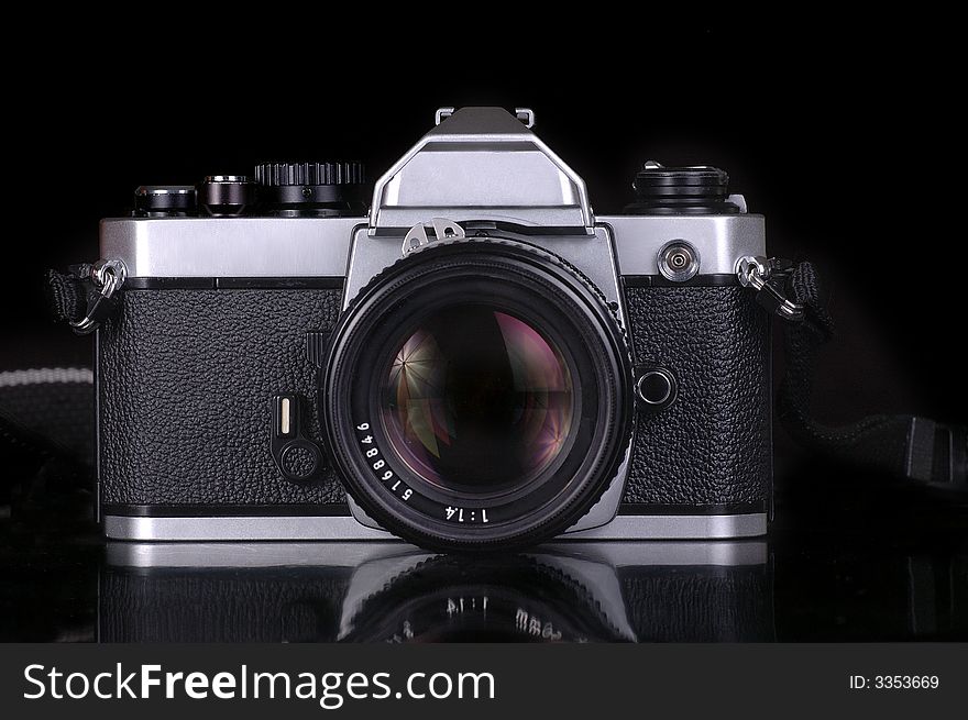 A mechanical SLR film camera against a black background. A mechanical SLR film camera against a black background.