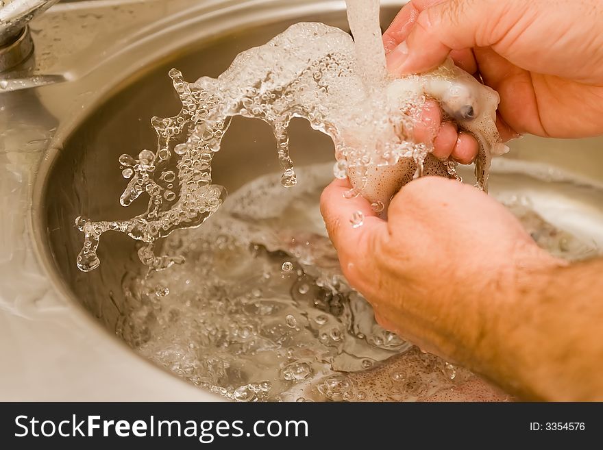 Preparing fresh calamari under cold water. Preparing fresh calamari under cold water