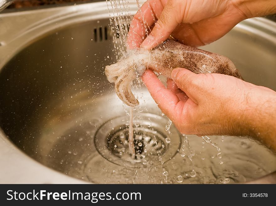 Preparing fresh calamari under cold water. Preparing fresh calamari under cold water