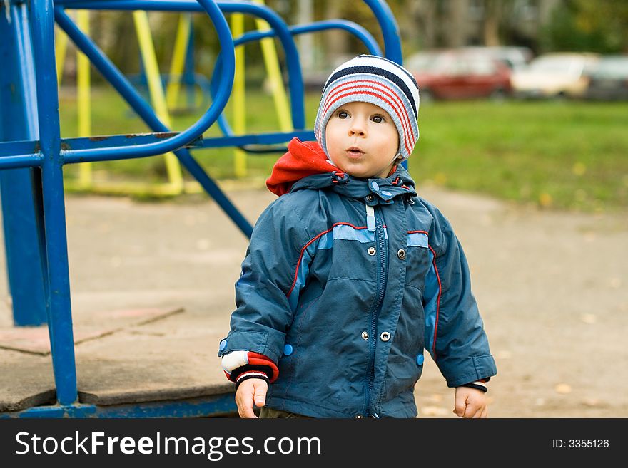 The child the boy on a children's playground at a swing. The child the boy on a children's playground at a swing