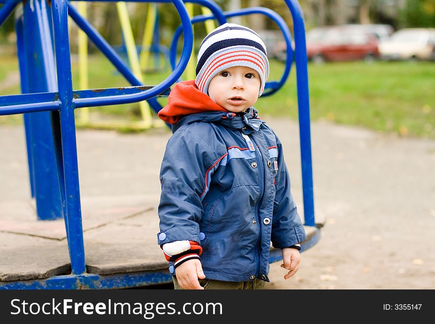 The child the boy on a children's playground at a swing. The child the boy on a children's playground at a swing