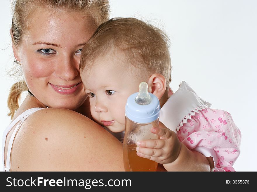 Happy mother holds on hands of the baby with a bottle. Happy mother holds on hands of the baby with a bottle