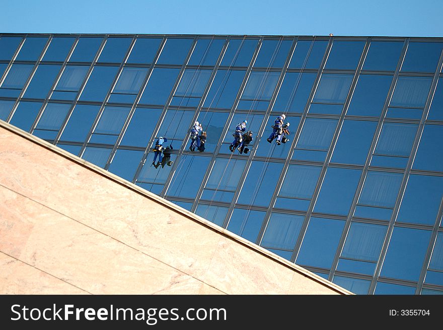 Four cleaners washing the glass building. Four cleaners washing the glass building
