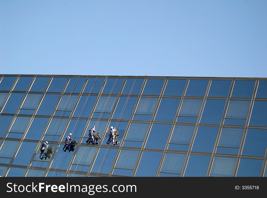 Four cleaners washing the glass building. Four cleaners washing the glass building