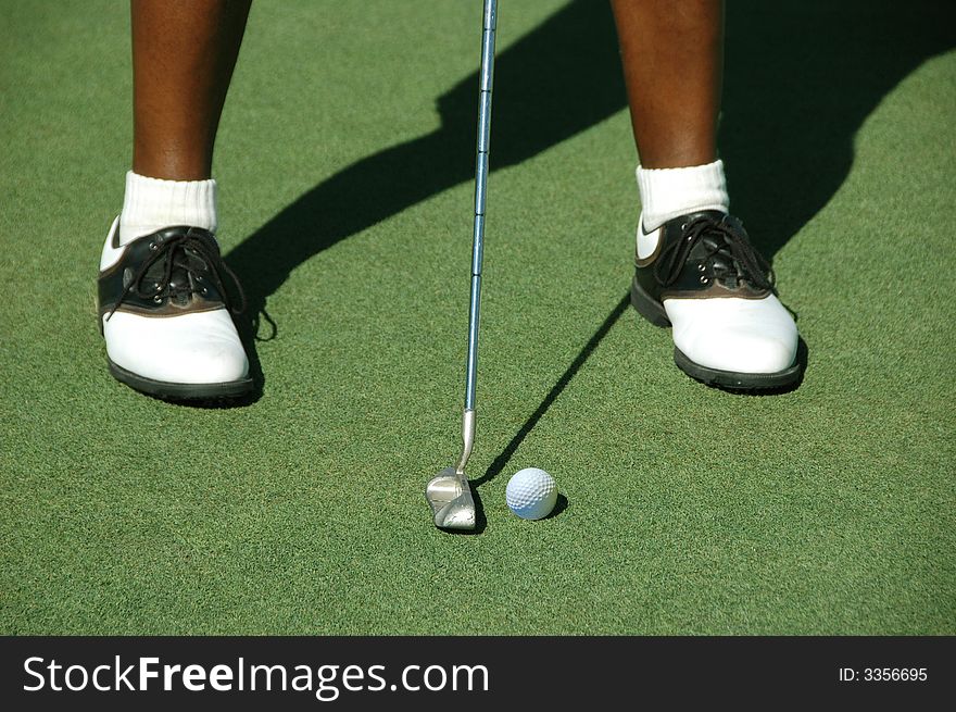 Golfer about to put showing feet and putter