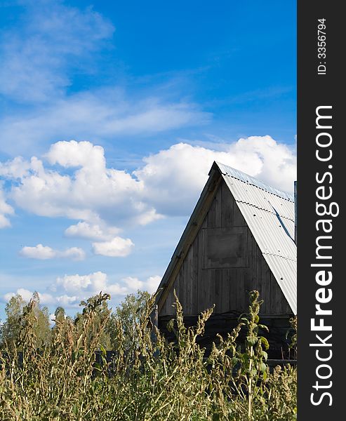 Photo of lonely village house with blue sky and clouds on the background. Photo of lonely village house with blue sky and clouds on the background