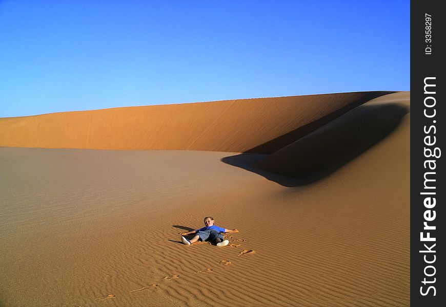 Little, lonely boy playing scarf on a great desert. Little, lonely boy playing scarf on a great desert