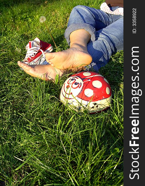 Bare feet, and red snickers resting on grass. Bare feet, and red snickers resting on grass