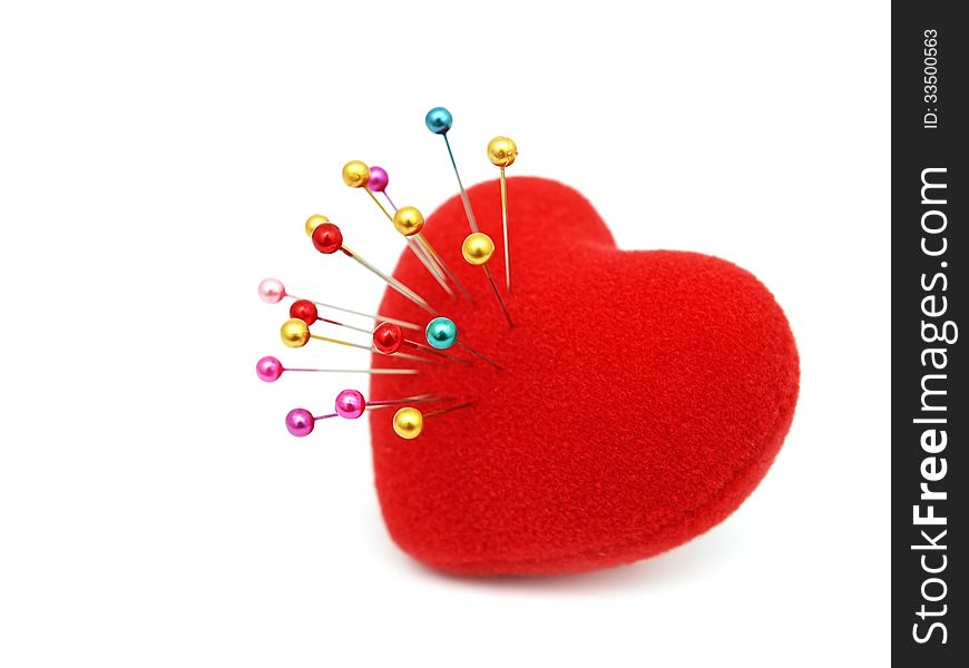 Red heart stabbed by pins on white background