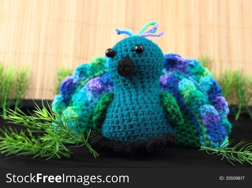 A handcrafted toy peacock crocheted from blue and green shades of yarn. A handcrafted toy peacock crocheted from blue and green shades of yarn.