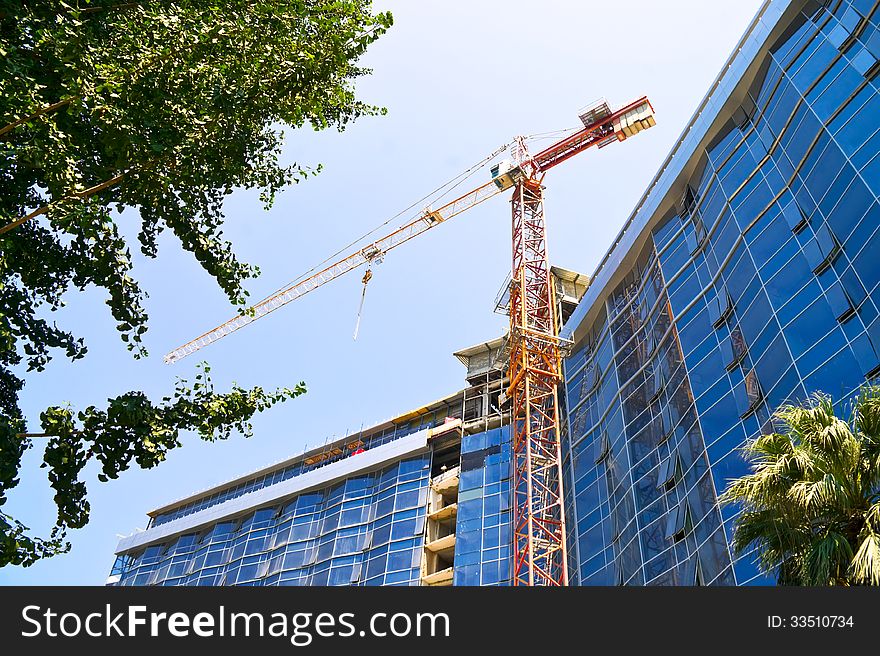 Elevating crane on the background of hotel under construction