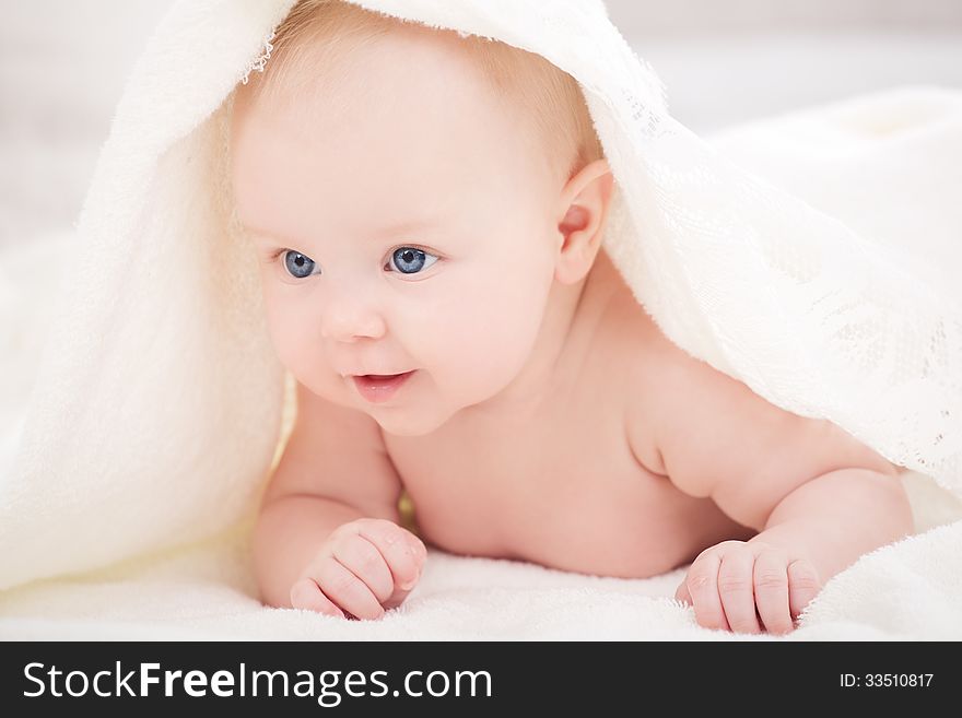 Smiling baby looking at camera under a white blanket/towel. Smiling baby looking at camera under a white blanket/towel