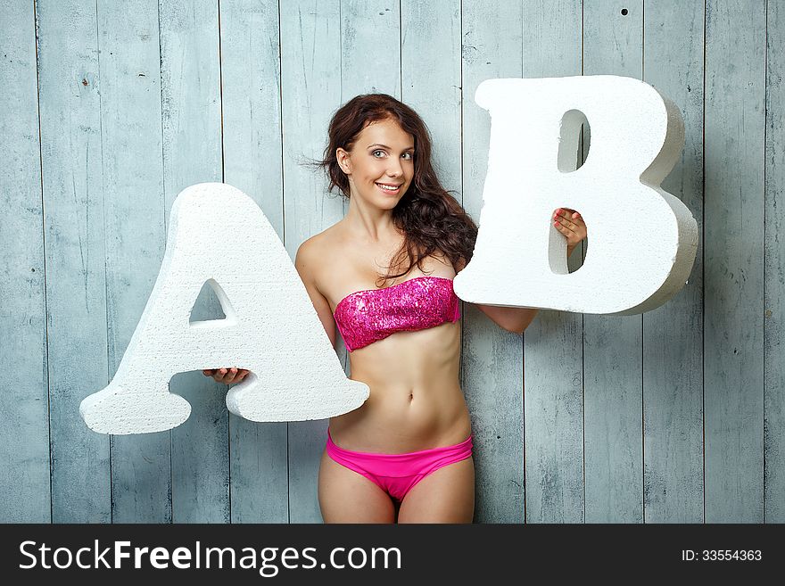 Beautiful girl in a bathing suit holds in hands letters. Beautiful girl in a bathing suit holds in hands letters