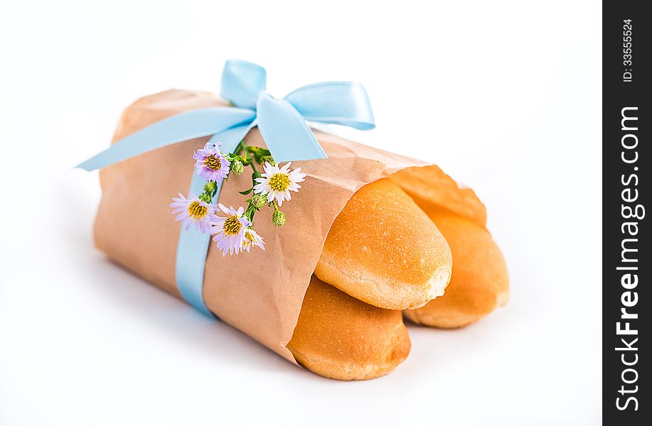 Fresh buns in paper bag decorated with ribbon and flowers isolated on white