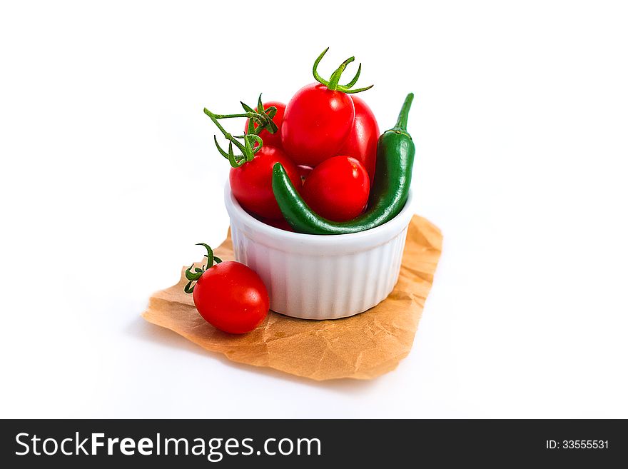 Tomato and chili peppers in white cup isolated on white