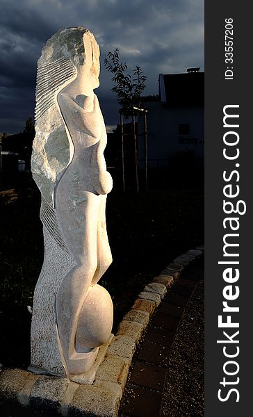 An abstract statue of stone representing mother earth, taken in artificial light at night. An abstract statue of stone representing mother earth, taken in artificial light at night.