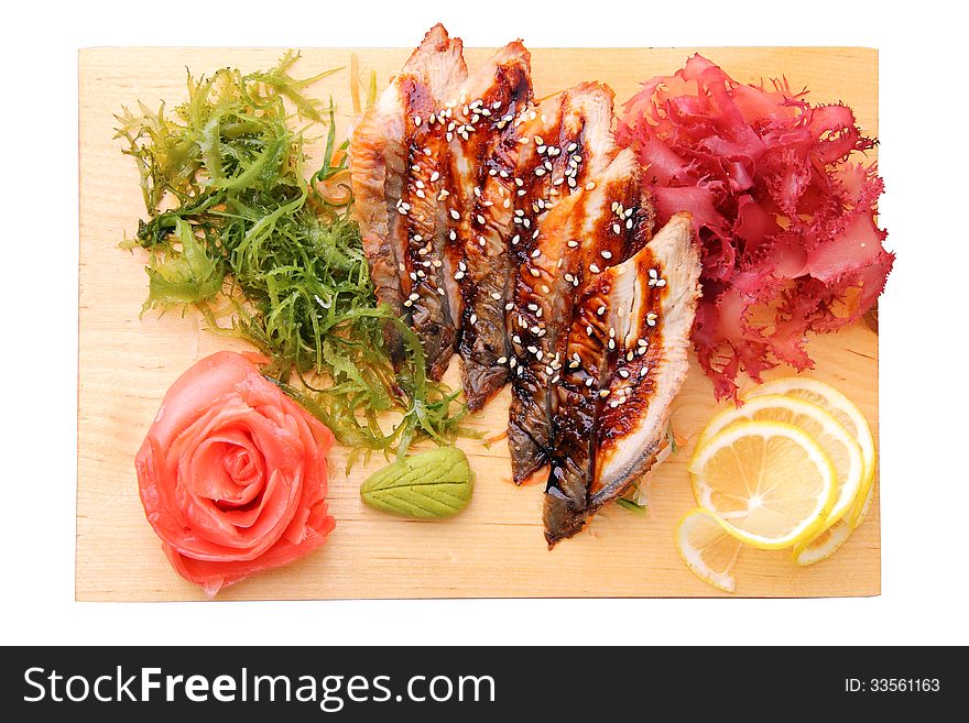 Sashimi unagi with slices of eel, lemon lobules, ginger, wasabi, red and green algae on rectangular board isolated on a white background. Top view. Sashimi unagi with slices of eel, lemon lobules, ginger, wasabi, red and green algae on rectangular board isolated on a white background. Top view.