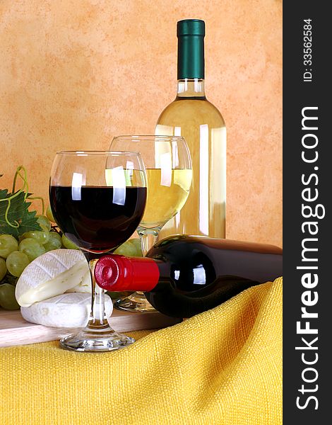 Red wine and white wine with glass in the foreground alongside cheese and grapes. Red wine and white wine with glass in the foreground alongside cheese and grapes