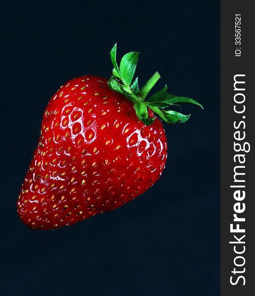 Single Ripe Strawberry Against Black Background. Single Ripe Strawberry Against Black Background