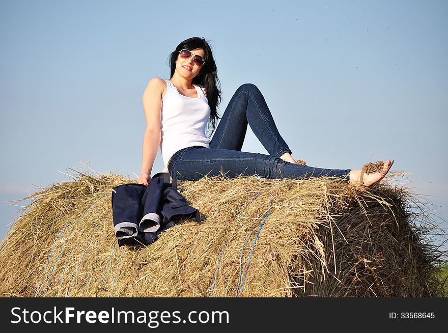 Beautiful girl sit on haystacks
