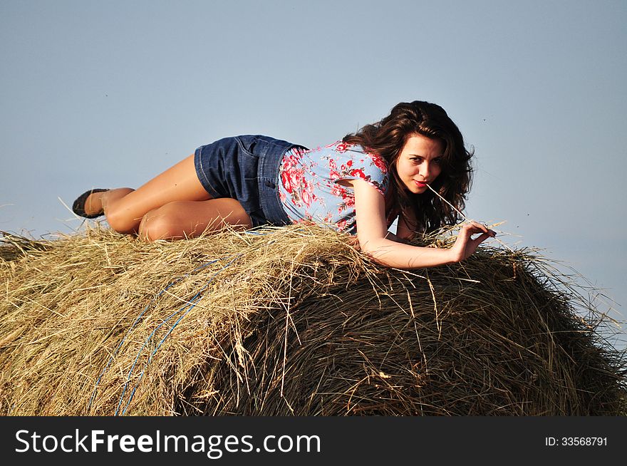 Beautiful girl sit on haystacks