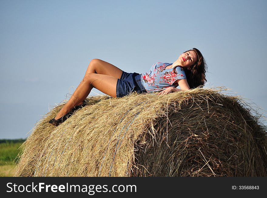 Beautiful girl sit on haystacks