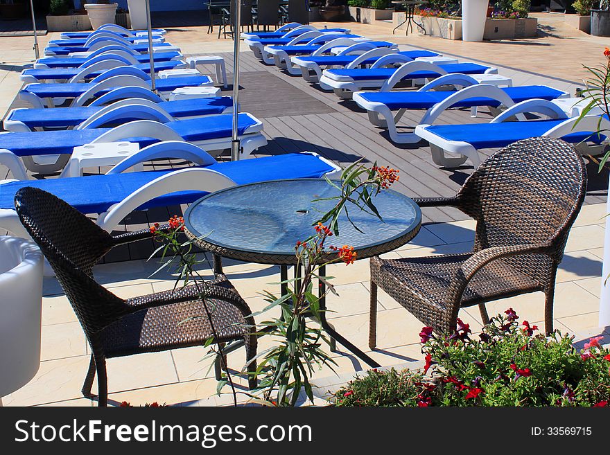 Sunny outdoor sunbeds and patio furniture with decorative flower in front