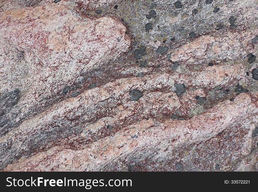 Surface of natural dark red stone (crimson quartzite porphyry) with black spots as background. Surface of natural dark red stone (crimson quartzite porphyry) with black spots as background