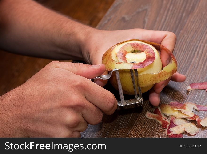 One hands peel an apple with a tool