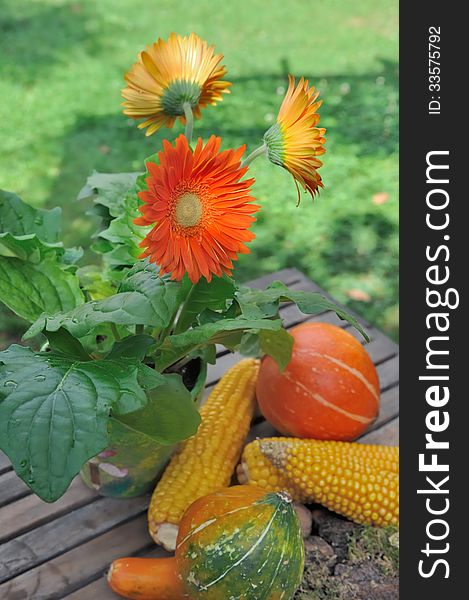 Colorful flowers and vegetables placed on a wooden table after after picking