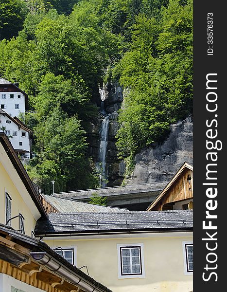 Waterfalls betweens traditional house on the alps cliff in Hallstatt Austria. Waterfalls betweens traditional house on the alps cliff in Hallstatt Austria