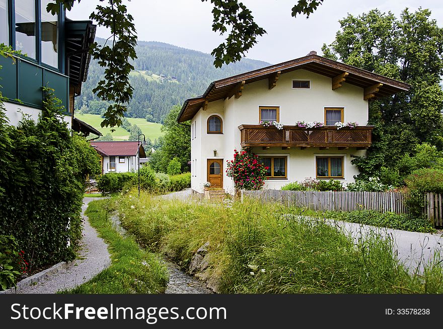 Traditional wooden houses with water stream near bybackground of the alps