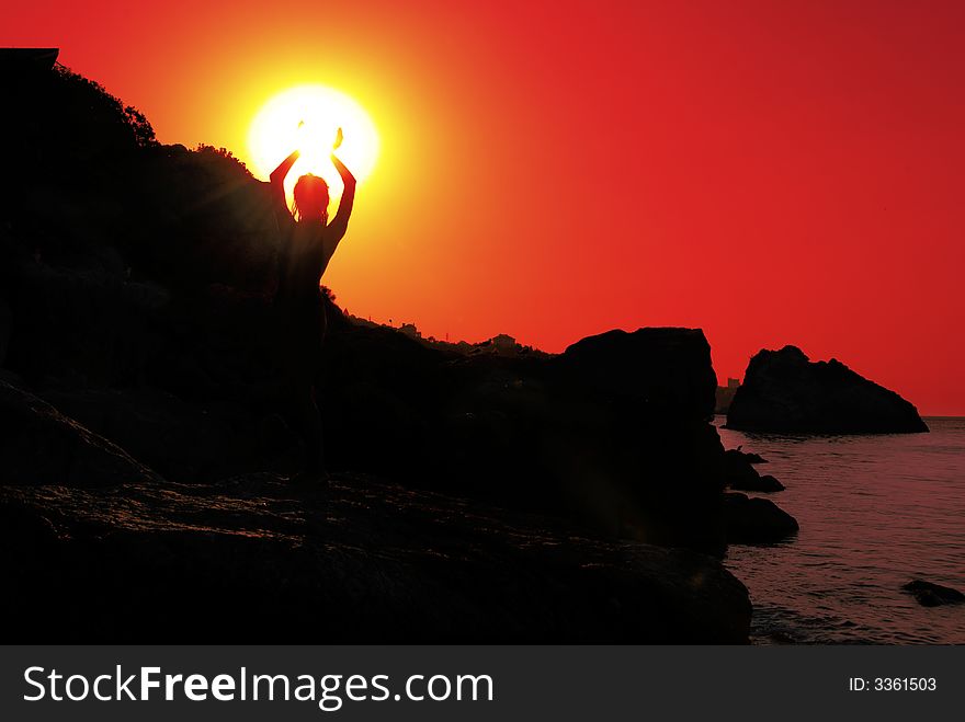 Silhouette of a girl on the coastline on the sunset