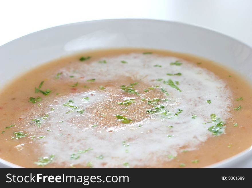 Cream of pumpkin soup with a swirl of whipped cream and sprinkle of Chinese parsley