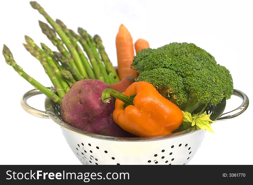 Fresh vegetables - asparagus, carrots, broccoli, batat and capsicum in steel colander with water drops. On white background, isolated. Shallow DoF. Fresh vegetables - asparagus, carrots, broccoli, batat and capsicum in steel colander with water drops. On white background, isolated. Shallow DoF.