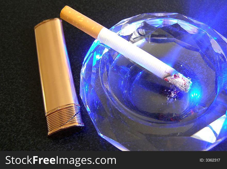 Cigarette in ashtray and lighter on the black table. Cigarette in ashtray and lighter on the black table