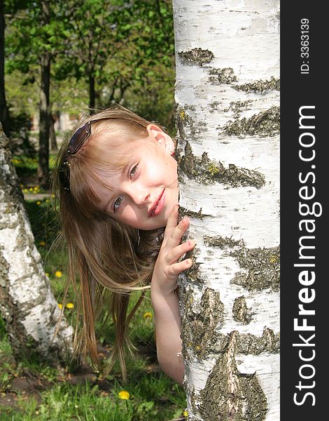 Young girl near the birch looking at camera