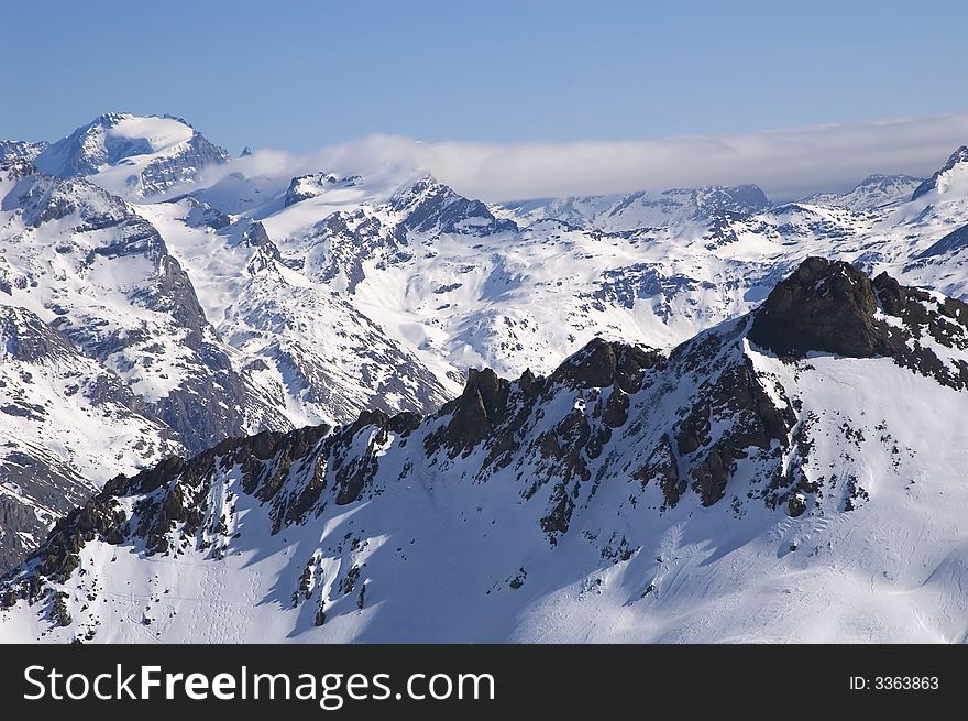 Snowed mountainrange with visible rocks
 and cloud
