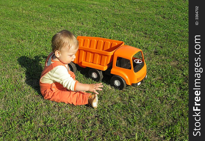 spring time, little baby boy play with car on the garden