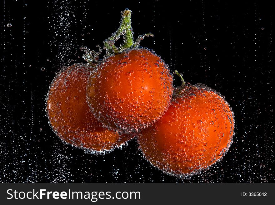 Fresh, clean tomatoes in clear, bubbly liquid. Black background. Fresh, clean tomatoes in clear, bubbly liquid. Black background.